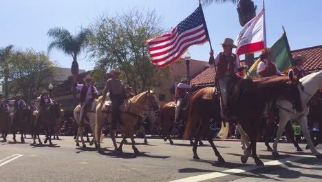 Cowboys-on-horseback-ride-through-a-small-town-during-a-4th-of-July-parade