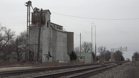 An-Amtrak-passenger-train-roars-by-a-small-town-silo-in-the-midwest-at-high-speed