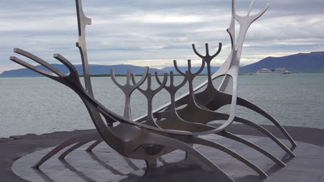 A-sculpture-of-a-viking-ship-stands-at-Reykjavik-Iceland-harbor-with-cruise-ship-background