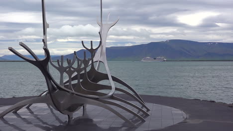 A-sculpture-of-a-viking-ship-stands-at-Reykjavik-Iceland-harbor-with-cruise-ship-background-1