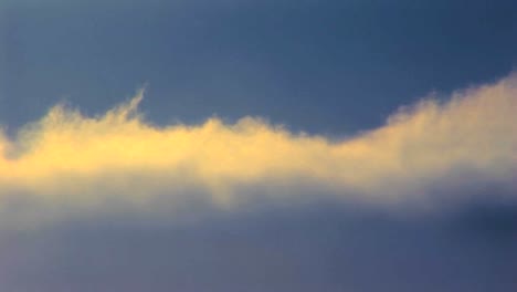 Time-lapse-shot-of-sun-lit-clouds-moving-beneath-a-blue-sky