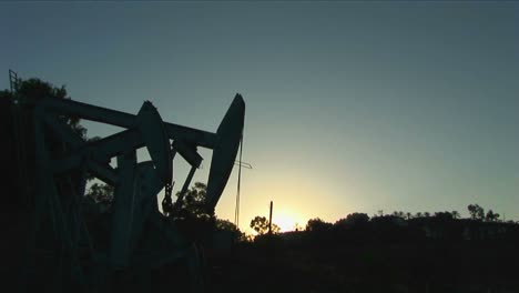 An-oil-well-derrick-is-silhouetted-against-a-glowing-sky