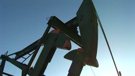 A-pump-jack-is-silhouetted-against-a-blue-sky