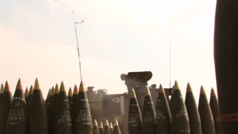 An-army-solider-in-Iraq-stands-amongst-shells-as-a-tank-gun-fires-