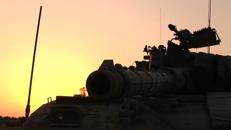 The-barrel-of-an-Israeli-tank-is-silhouetted-against-an-orange-sky