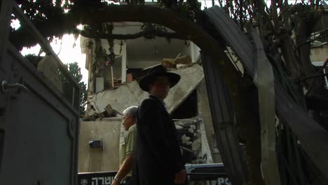 Pedestrians-in-Haifa-pass-by-an-apartment-building-destroyed-by-a-rocket-attack