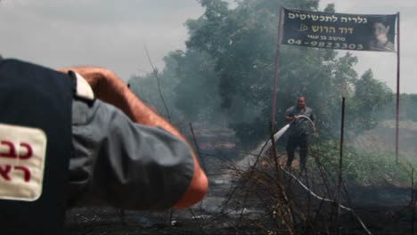 An-Israeli-police-officer-looks-on-as-fire-spreads-from-a-rocket-attack-in-Northern-Israel