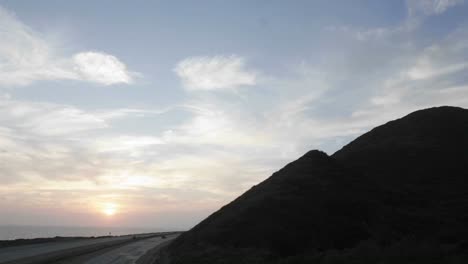 Time-lapse-of-clouds-moving-over-a-hillside-and-freeway-at-sunset
