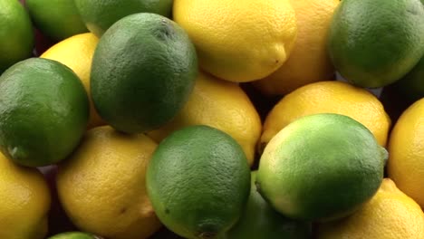 Zoome-Langsam-In-Gelbe-Zitronen,-Die-Auf-Einem-Haufen-Mit-Grünen-Limetten-Sitzen