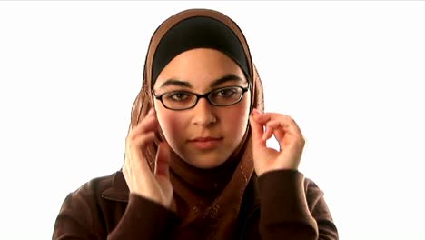 A-woman-wearing-an-underscarf-headscarf-and-sweater-puts-on-her-glasses