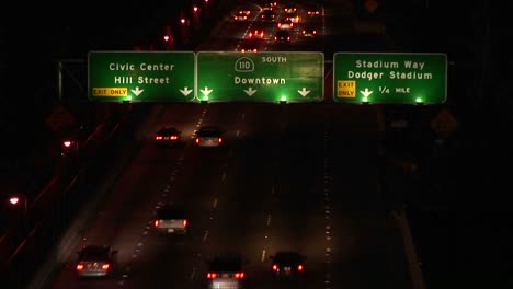 A-time-lapse-of-vehicles-driving-on-the-freeway-and-under-signs-at-night