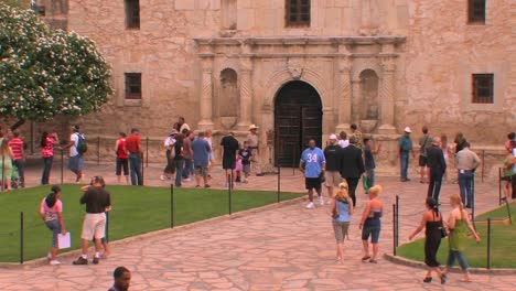 People-walk-around-a-stone-courtyard-and-building-in-San-Antonio-Texas