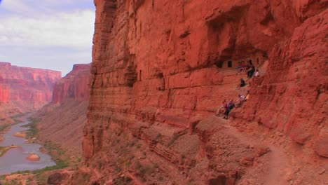 A-beautiful-shot-of-tourists-on-a-trail-along-the-Grand-Canyon-at-magic-hour