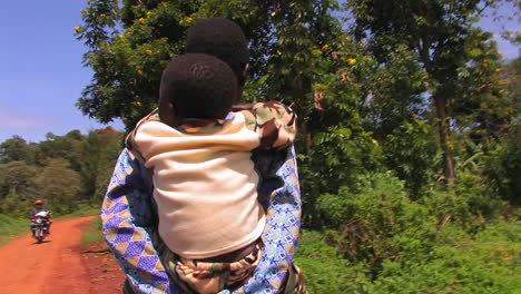 A-mother-carries-a-child-on-a-rural-dirt-road
