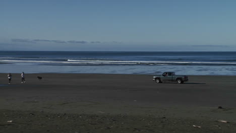 A-truck-drives-across-a-beach-with-a-dog-running-in-front