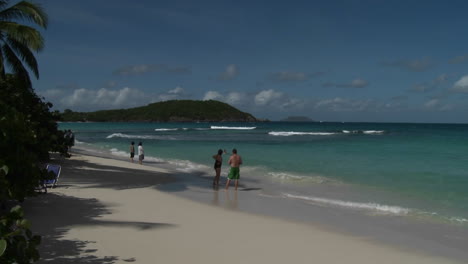 People-stroll-along-an-island-beach-in-the-Caribbean