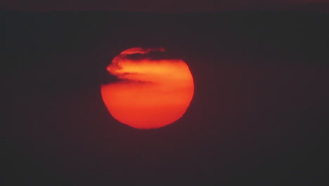 The-sun-slowly-sets-through-the-clouds-in-a-huge-orange-ball