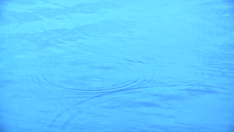 Water-drops-hitting-an-expanse-of-very-blue-water-
