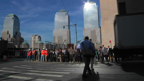 Construction-workers-and-pedestrians-pass-along-a-crosswalk-on-a-busy-urban-street-