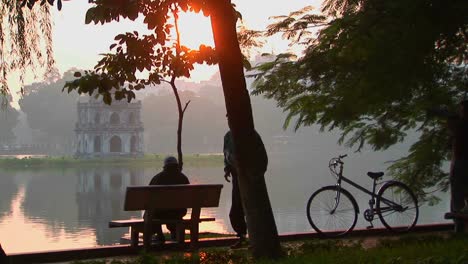 People-sit-in-a-park-in-Hanoi-at-sunset-and-admire-the-view