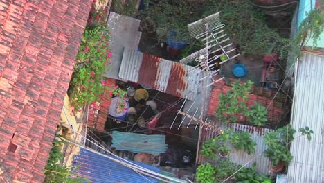 Pull-back-from-a-woman-working-on-a-rooftop-to-reveal-a-small-Vietnamese-neighborhood
