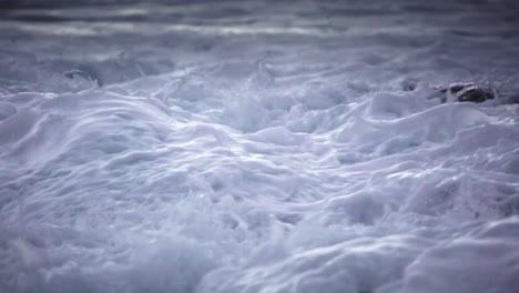 Water-level-view-of-waves-crashing-and-rolling-into-a-rocky-shore-in-slow-motion