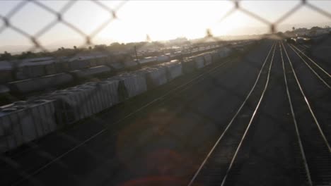 A-time-lapse-shot-through-a-chain-link-fence-of-a-railway-freight-yard