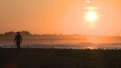 Surfer-Silhouette,-Die-Bei-Sonnenaufgang-Am-Surfers-Point-In-Ventura,-Kalifornien,-Aus-Dem-Wasser-Steigt