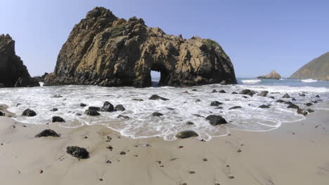 Low-angle-time-lapse-of-waves-breaking-through-a-rock-at-Pfeiffer-Beach-in-Big-Sur-California