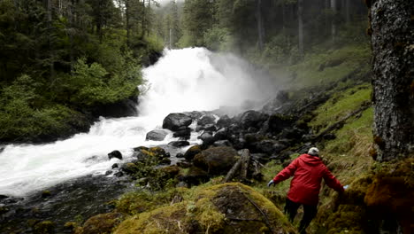 A-tourist-hiking-through-the-rainforest-to-Cascade-Creek-waterfall-in-Thomas-Bay-Southeast-Alaska