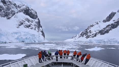 POV-of-ship's-bow-with-tourists-in-the-ice-of-Lemaire-Channel-in-Antarctica-