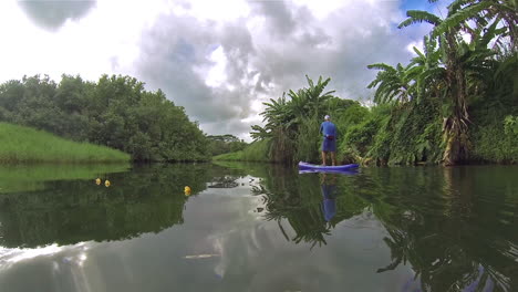 Ein-Mann-Rudert-Ein-Paddleboard-Einen-Fluss-Hinunter-In-Kauai-Hawaii-3