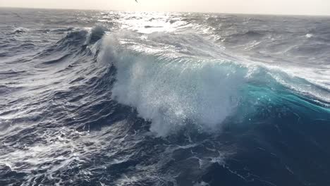Schöne-Zeitlupe-Von-Riesigen-Blauen-Meereswellen,-Die-Von-Einem-Boot-Aus-Ragen