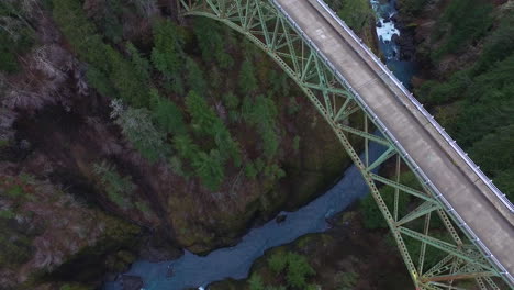 An-aerial-over-a-pickup-truck-traveling-over-a-steel-suspension-bridge-over-the-Skokomish-River-in-Washington-USA
