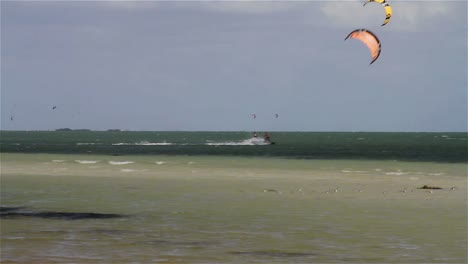 People-engage-in-the-fast-moving-sport-kite-boarding--along-a-sunny-coast