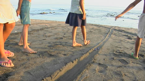 Bali-Kinder-Spielen-Ein-Spiel,-Das-Kronkorken-Den-Strand-Hinunterrollt