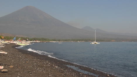 Catamarans-Are-Beached-Along-A-Shore-At-The-Base-Of-A-Volcano