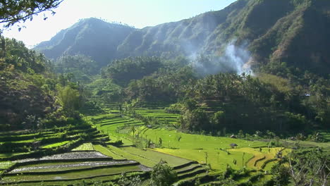 Mist-Seeps-Down-A-Mountainside-Above-Green-Terraced-Rice-Paddies