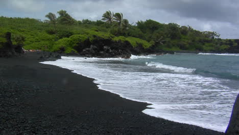 Las-Olas-Ruedan-Hacia-Una-Playa-De-Arena-Negra-En-Hawaii