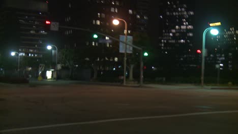 Ein-Auto-Fährt-Nachts-Eine-Straße-Entlang-In-Der-Jahrhundertstadt-Los-Angeles,-Wie-Durch-Die-Heckscheibe-In-Einem-Winkel-Gesehen