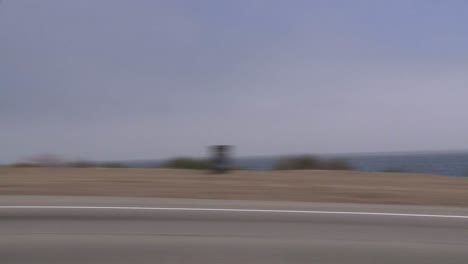 A-Car-Travels-Along-Pacific-Coast-Highway-As-Seen-Through-The-Side-Window-3