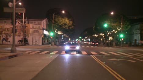 Un-Automóvil-Viaja-Por-Una-Calle-De-Noche-En-Santa-Mónica,-California,-Visto-A-Través-De-La-Ventana-Trasera-4