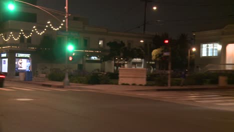 Un-Automóvil-Viaja-Por-Una-Calle-De-Noche-En-Santa-Mónica,-California,-Visto-A-Través-De-La-Ventana-Trasera-En-Un-ángulo-1