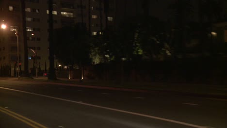 Un-Automóvil-Viaja-Por-Una-Calle-De-Noche-En-Santa-Mónica,-California,-Visto-A-Través-De-La-Ventana-Trasera-En-Un-ángulo-4