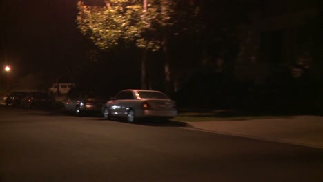 A-Car-Travels-Along-A-Street-At-Night-In-Los-Angeles-California-As-Seen-Through-The-Rear-Window-At-An-Angle