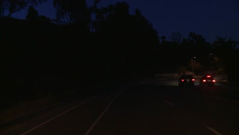 Ein-Auto-Fährt-Nachts-Eine-Gewundene-Straße-In-Los-Angeles,-Kalifornien,-Durch-Die-Heckscheibe-Gesehen