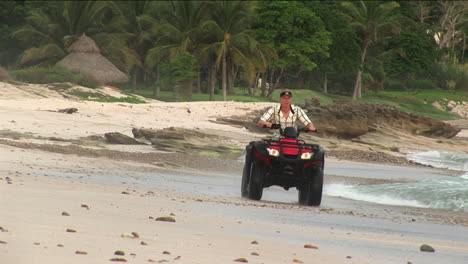 A-man-rides-an-ATV-through-the-water-on-a-beach-1