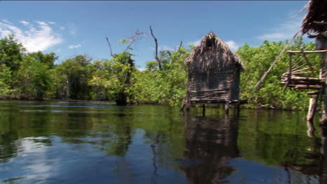 Thatchedroofed-homes-on-stilts-stand-in-a-tropical-river-area-1
