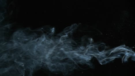 Cigarette-smoke-is-being-blown-in-against-a-black-background