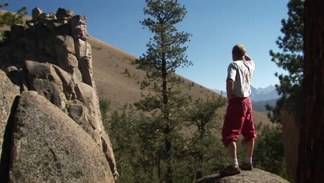 A-man-steps-up-onto-a-boulder-and-looks-into-the-distance
